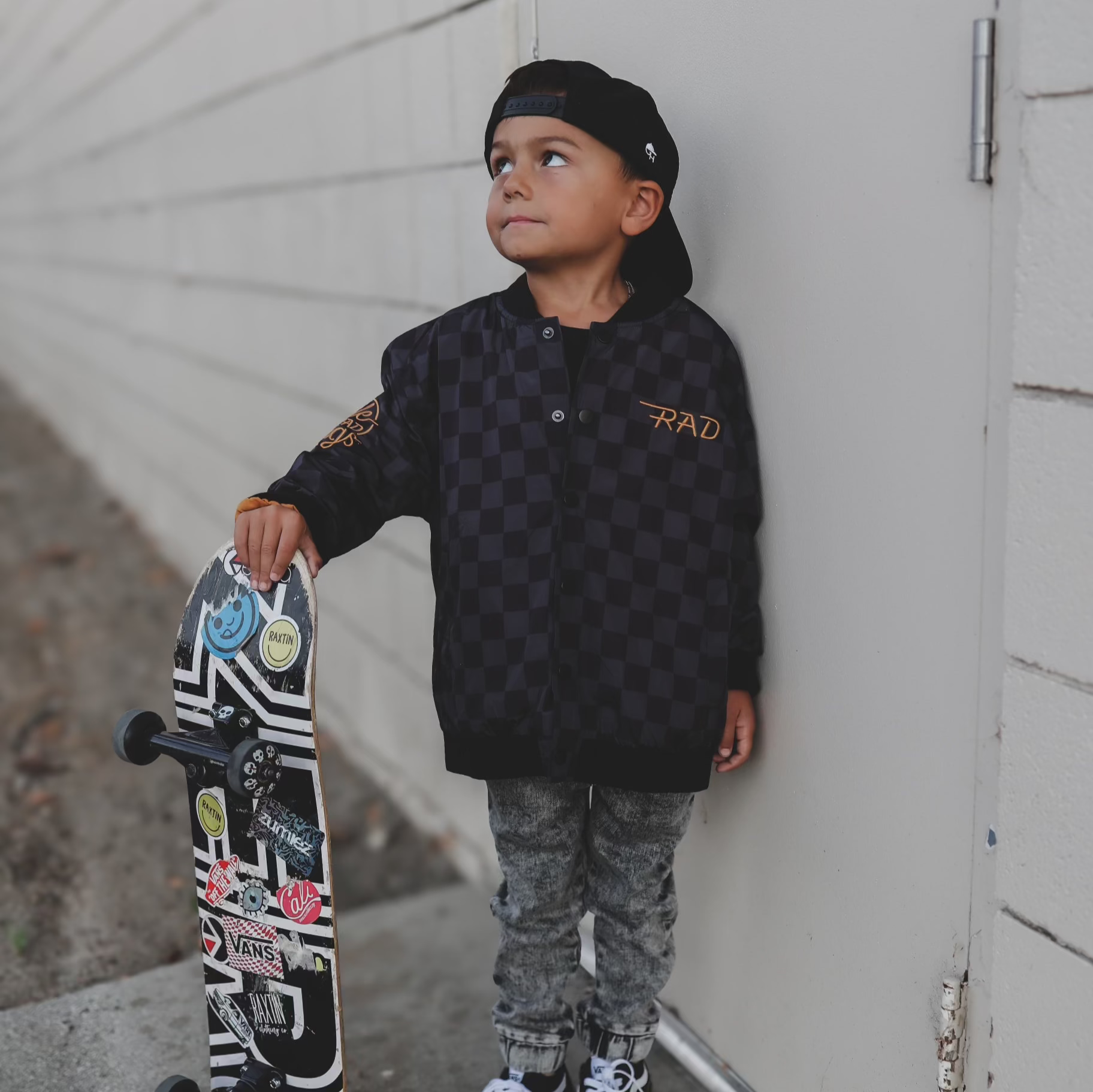 Child wearing a checkered waterproof letterman jacket